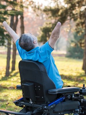 Happy man in electric wheelchair with hands up.