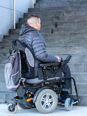 young disabled man in wheelchair in front of stairs