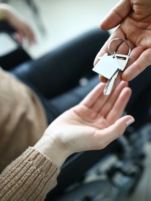 A woman in a wheelchair receives the keys to the house from the hands of a man.